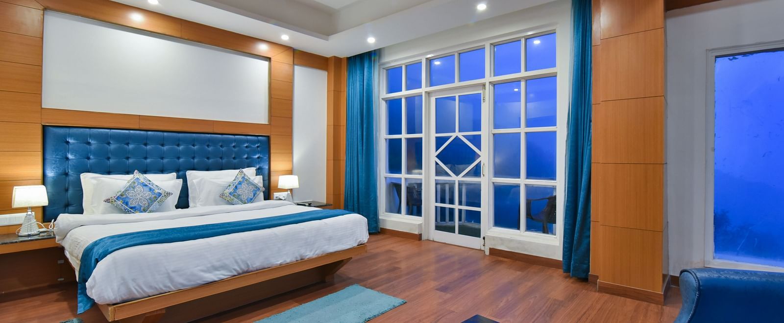 A large bed placed in front of the sofas in Luxury Room with Balcony at DLS Highland Resort and Spa, Mussoorie.